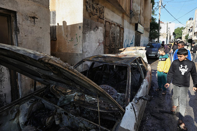 Palestinians check a burnt car in the village of Al-Fara