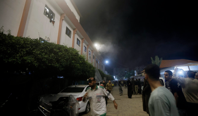 Palestinians look at smoke raising from the patient room